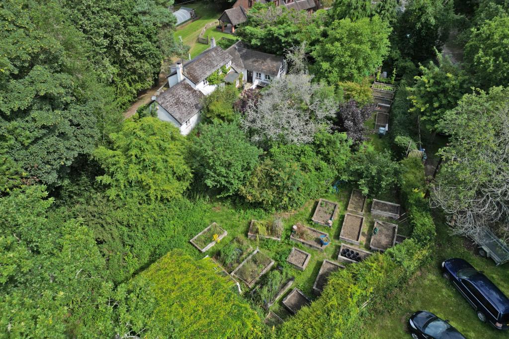 Lot: 113 - DETACHED COTTAGE FOR IMPROVEMENT ON 0.3 ACRE PLOT - Aerial shot showing cottage and grounds